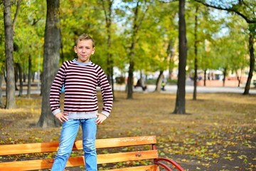 Obraz premium The young guy sits on a bench in park