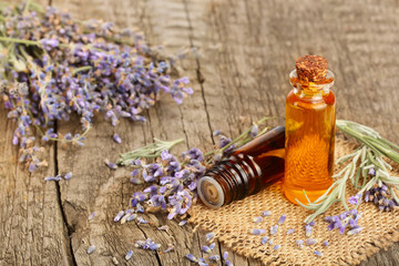 Herbal oil and lavender flowers on old wooden background