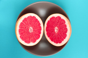Grapefruit cut in half in a plate on a blue background