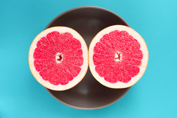 Grapefruit cut in half in a plate on a blue background