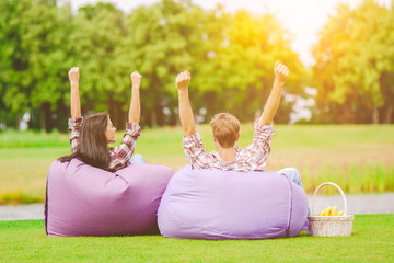 The man and woman sit on the bean bag and gesture