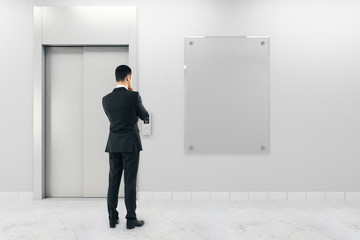Businessman with poster and elevator