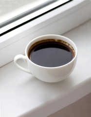 white big americano cup of coffee on the windowsill