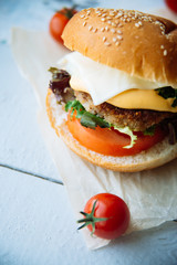 Two hamburgers with beef burger cutlet, fried onion, spinach, ketchup sauce and blue cheese in traditional buns, served on wood chopping board over bright turquoise background. Copy space