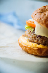 Tasty burger with beef with spinach and blue cheese served on a small board on a wooden background.