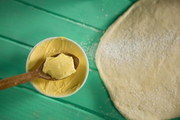 Overhead view of butter in bowl by rolled dough