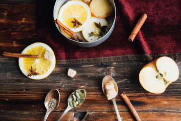 Mulled wine in rustic mug with spices and ingredients on wooden background. Top view, flat lay. Retro toned photo. Copy space for your text.