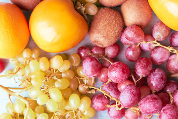 Persimmon, kiwi, orange and grapes on a blue wooden background