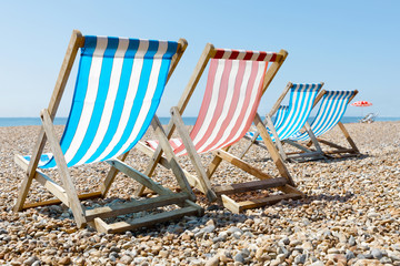 Colorful empty red and blue deckchairs and a parasol on the beach © hans_chr