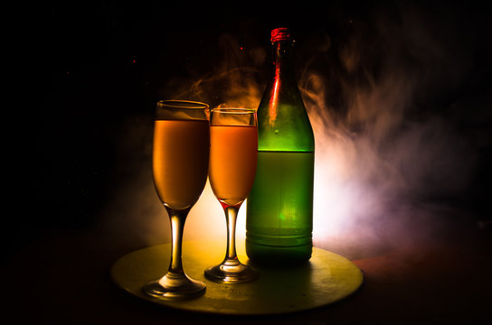 two glasses of wine and bottle over toned foggy background. Image of two wine glasses with champagne the outlines and silhouettes , dark background.