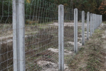 Fence in the suburban area with a forest near the trees. Fencing of private territory. Refugee shelter in Europe