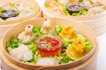 Close up various dim sum and sauce in bamboo steamer on the white background isolated. Chinese cuisine, selective focus