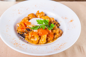 Chinese chicken sweet and sour sauce, served with rice in the white plate on the craft paper background. Selective focus