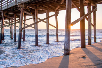 Evening sunset on the wooden structures of a pier. Summer days come to a end on the california coast