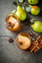 Autumn drinks. Mulled wine. Traditional autumn spicy cocktail with pear, cider and chocolate syrup, with cinnamon, anise, brown sugar. On black stone table. Copy space