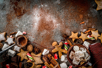 Fototapeta na wymiar New Year, Christmas treats, sweets. Cup of hot chocolate with fried marshmallow, ginger star cookies, gingerbread men, striped candy, spices cinnamon anise, cocoa, powdered sugar. Top view copy space