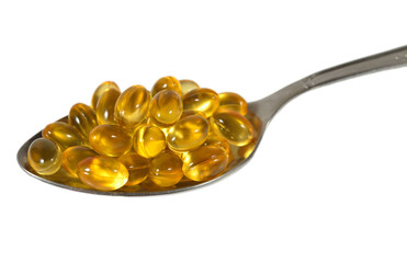 Omega-3 fish fat oil capsules in spoon on a white