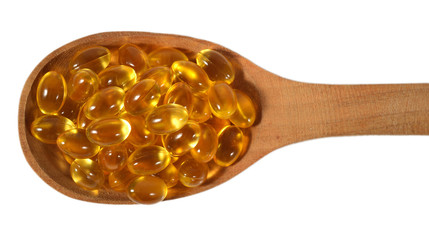 Omega-3 fish fat oil capsules in wooden spoon on a white