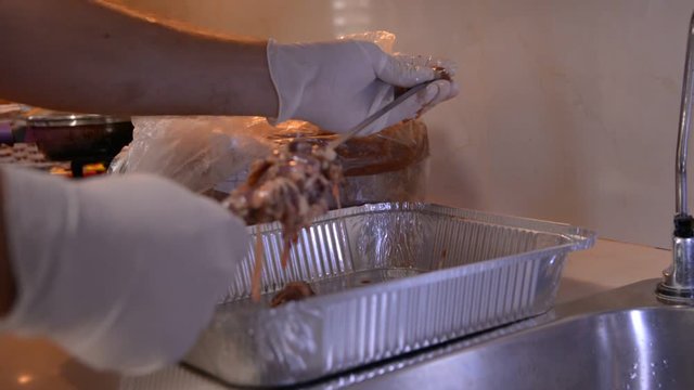 men hands in white gloves prepering raw chicken hearts for bbq on kitchen