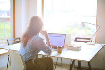Young woman sitting in office table, looking at laptop computer screen . Young woman