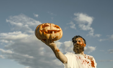 Halloween pumpkin with red blood in zombie hand on foreground