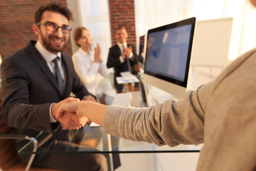 businessman shaking hands with a business partner sitting near your desktop