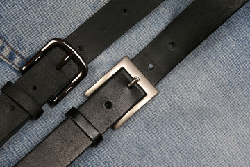 two black leather belt on a background of jeans.