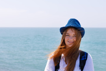 Girl with backpack on the sea coast