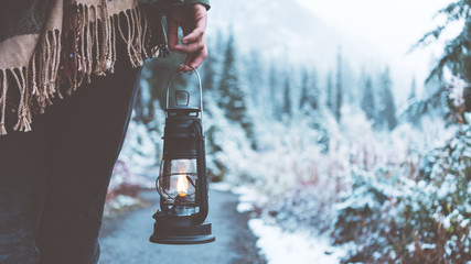 Woman traveling among snowy forest with kerosene lamp. Close-up. Wearing poncho. Winter is coming. Wanderlust and boho style © Alex from the Rock