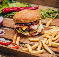Bacon burger with beef and french fries on wooden table