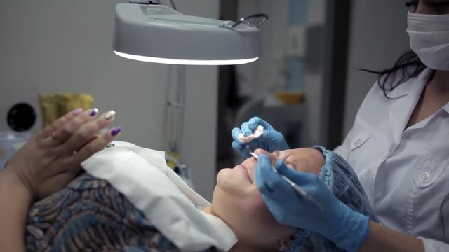 The beautician makes a cleansing of the nose area during the procedure of mechanical facial cleansing