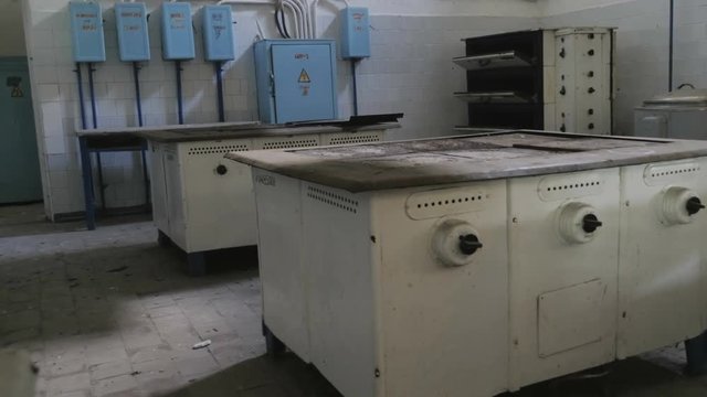 Old, dusty kitchen in a cafe, restaurant, public dining room. Dirty electric cooker, electric pressure cooker, ovens and tables
