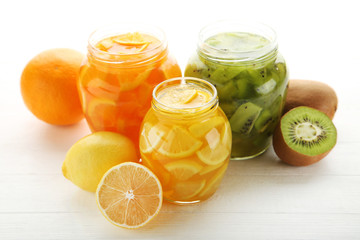 Lemon, kiwi and orange jam in glass jars on white wooden table