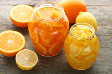 Lemon and orange jam in glass jars on wooden table
