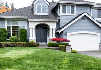 Clean home during autumn season with red maple and green front yard