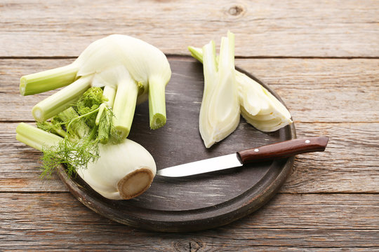 Ripe fennel bulbs with knife on grey wooden table