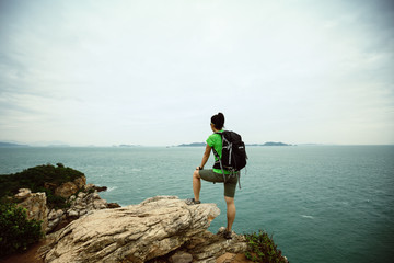 woman backpacker enjoy the view on seaside mountain top cliff