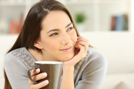 Pensive woman holding a coffee cup looking at side
