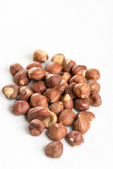 Pile of raw hazelnuts isolated above white marble stone