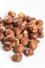 Pile of raw hazelnuts isolated above white marble stone