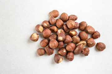 Pile of raw hazelnuts isolated above white marble stone