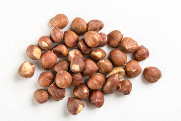 Pile of raw hazelnuts isolated above white marble stone