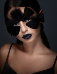 A beautiful girl with bright colored make-up and a collar of colored feathers on her face. Decoration,clothing.Fashion,beauty, make-up,magazine,photosession. Accessories,bijouterie,cosmetics.