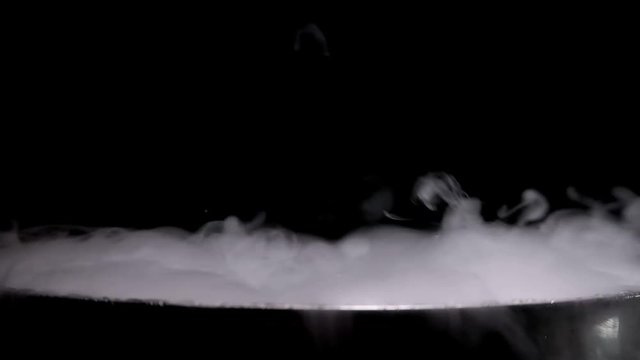 boiling pot of smoke on black background
