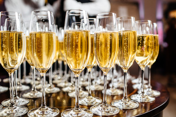  Elegant glasses with champagne standing in a row on serving table during party or celebration