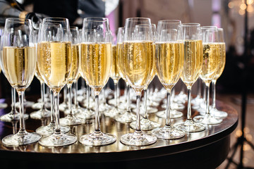  Elegant glasses with champagne standing in a row on serving table during party or celebration