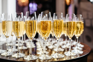  Elegant glasses with champagne standing in a row on serving table during party or celebration