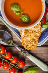 tomato and basil soup shot on wood boards top view with vine tomatoes loose basil spoon portrait