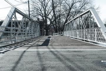 Steel bridge walkway on sunny day. Wooden and steel bridges with natural light and shadow. Outdoor park bridge footpath walkway. Tree and branch background. Nature and industrial background design.