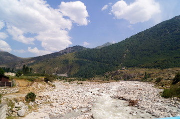 Clean fast river surrounded by mountains, landscape on a sunny day.